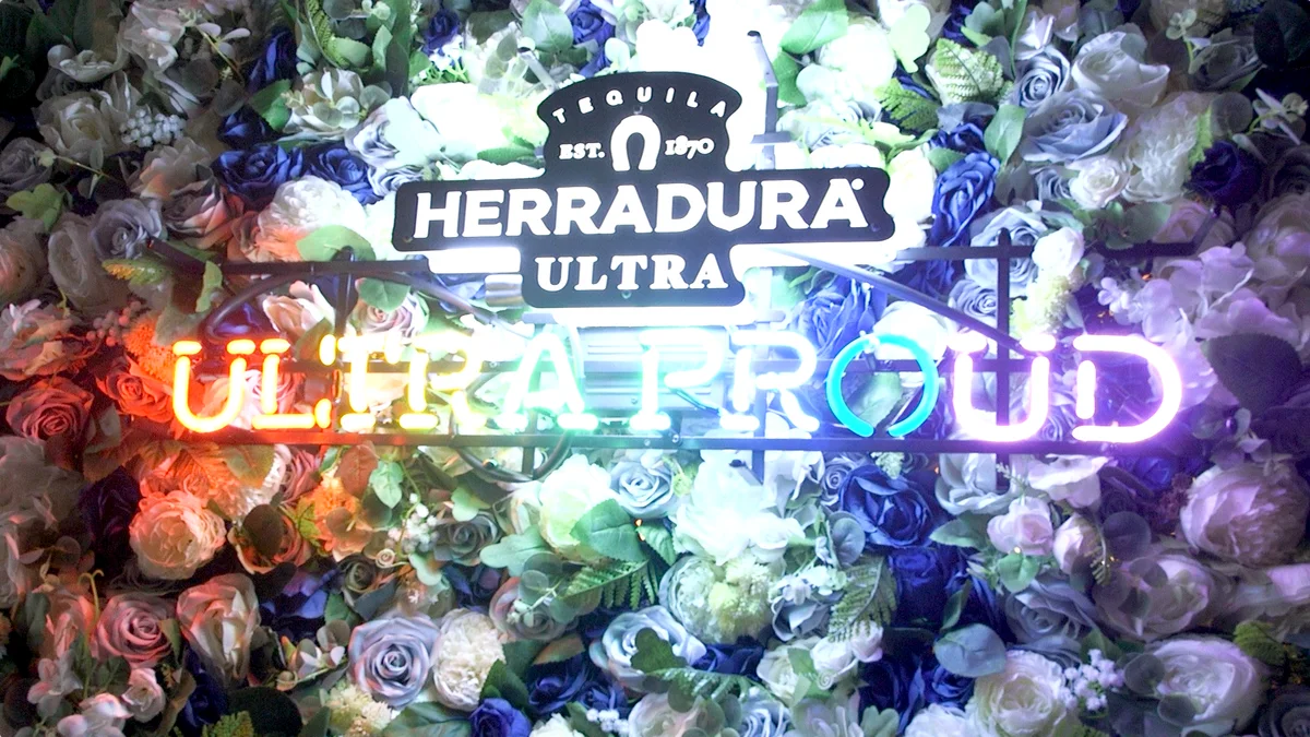 Herradura Ultra Proud sign displayed against a flower wall